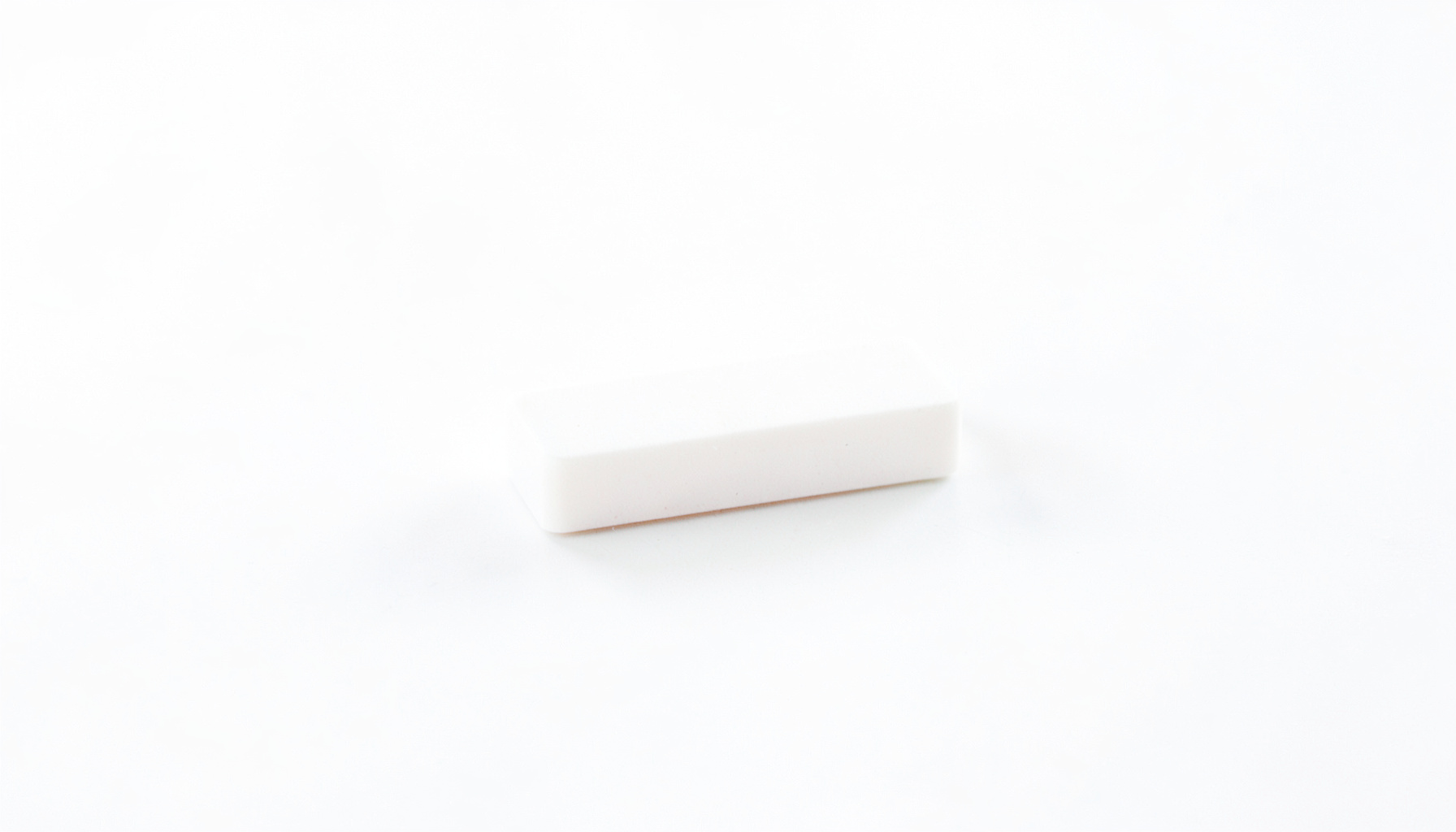 A single white tablet on a clean white surface under bright clinical lighting